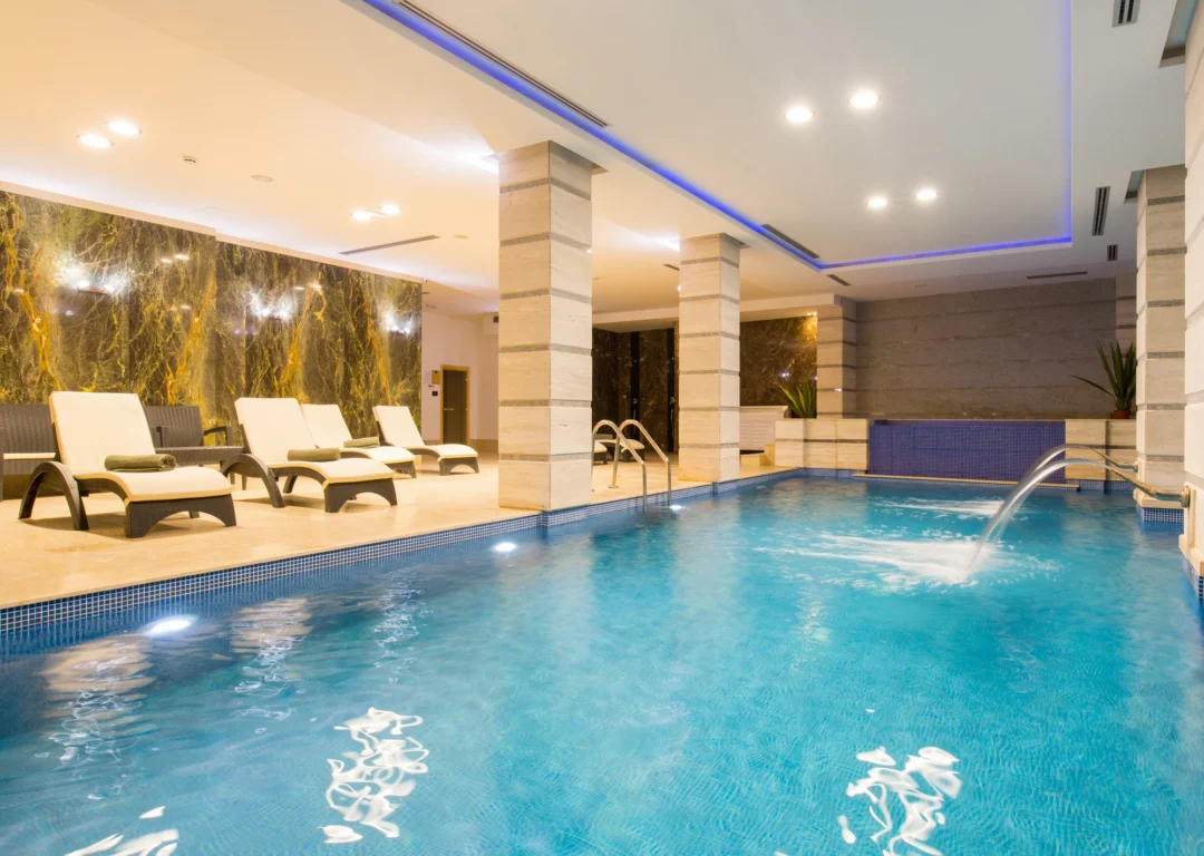 Indoor luxury pool with poolside chairs at a wellness centre.
