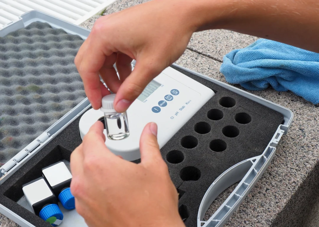 Hands testing water with a portable kit.