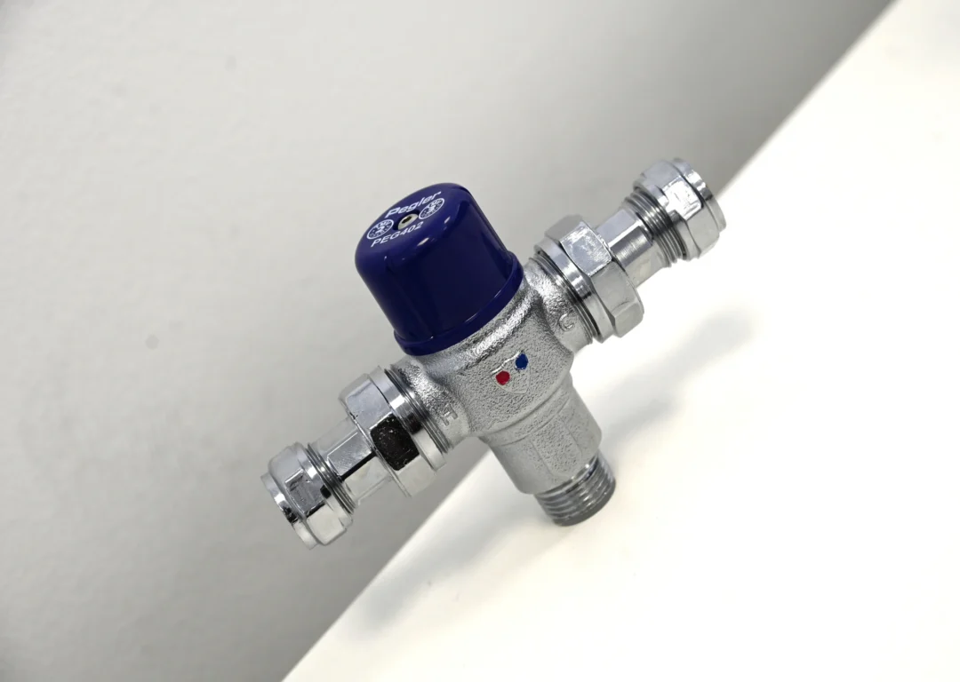A new, shiny silver thermostatic mixer valve with a blue cap.