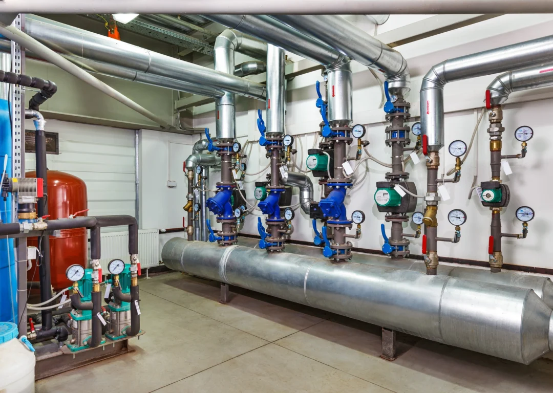 Industrial boiler room with pipes and pumps.