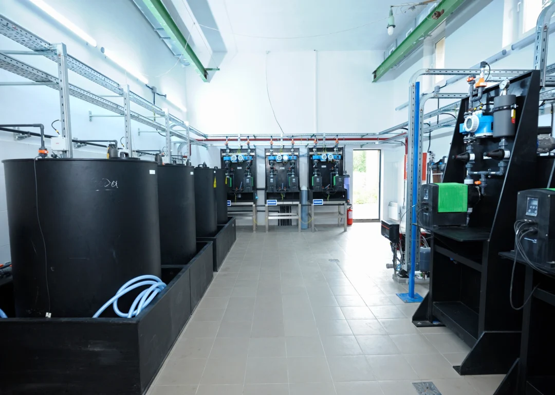 Industrial room with black tanks and chemical dosing equipment.